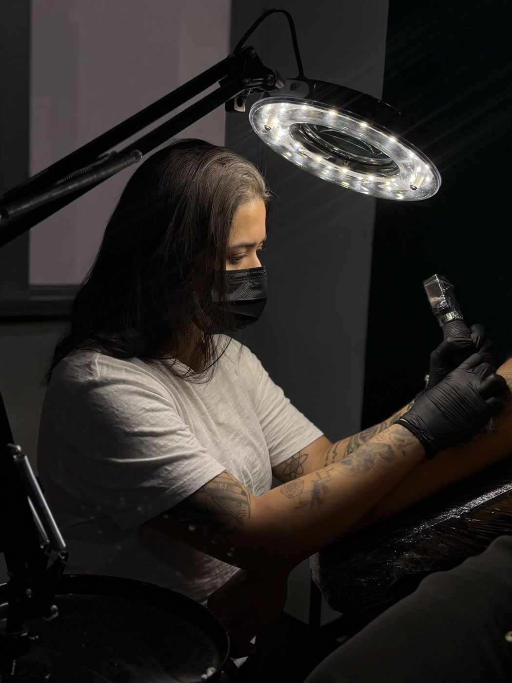 Giovanna Gomes tatuando sob a luminária